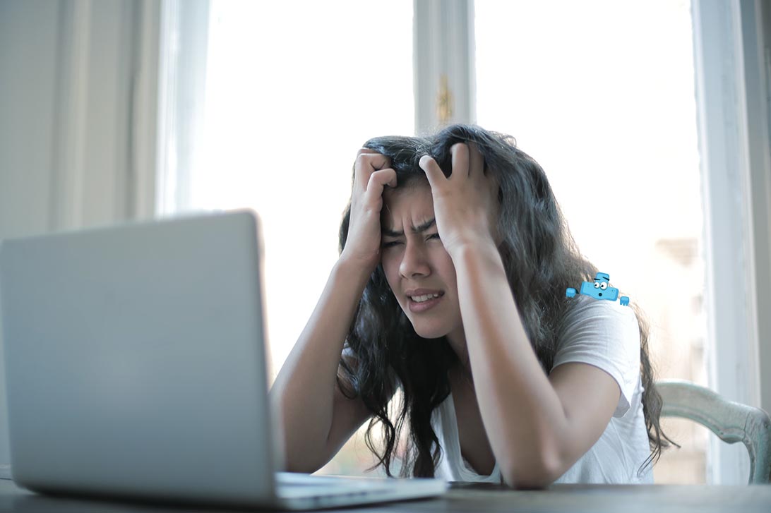 Sfrustrowana dziewczyna przed laptopem trzymająca się za głowę