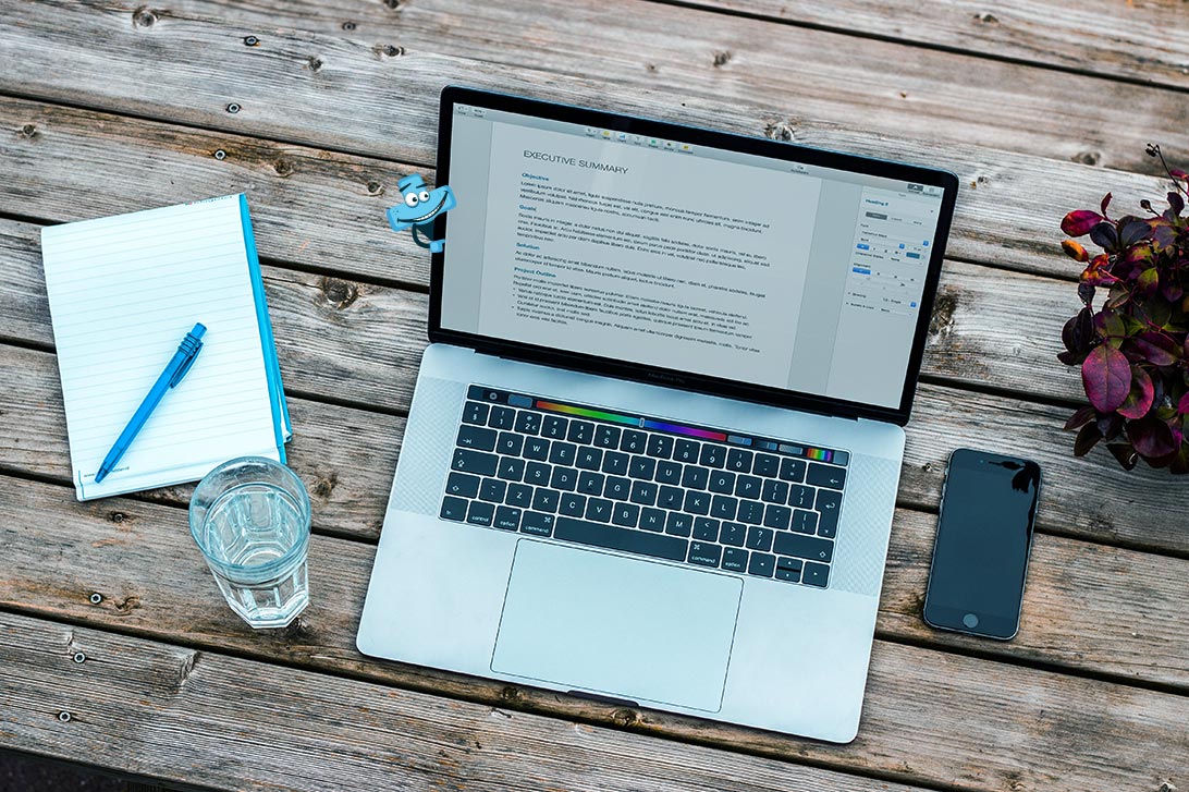 Laptop, notes, szklanka wody, biurko.