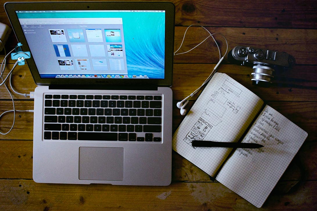 Laptop, notatnik, długopis na biurku.