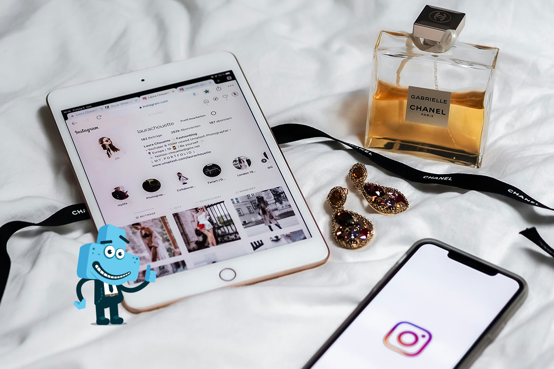 Na zdjęciu mamy tablet oraz telefon z włączoną aplikacją Instagram, całość dopełnia stojący obok ozdoby flakon perfum i biżuteria