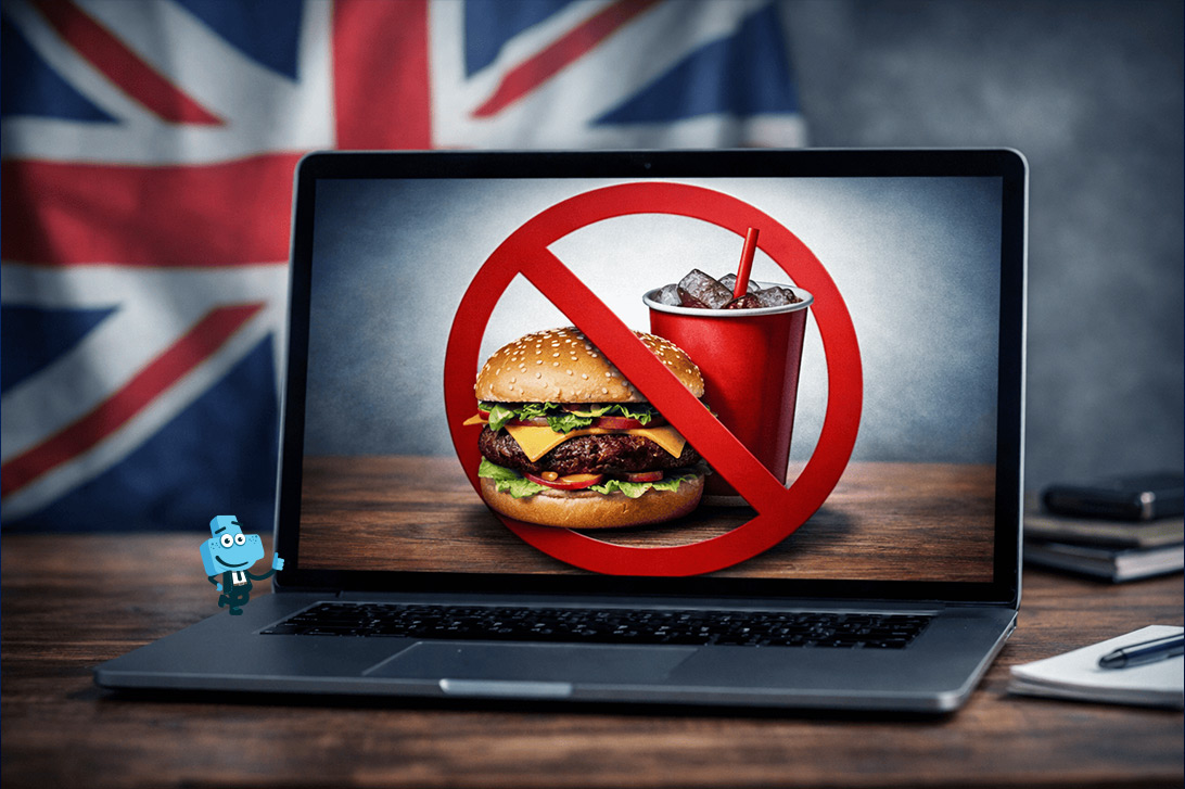 laptop stojący na stole, na jego ekranie przekreślone niezdrowe jedzenie, w tle flaga Wielkiej Brytanii